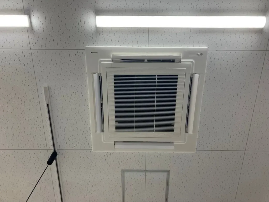 天井に設置された清掃後のカセット形室内機（Panasonic）。化粧パネルと吹き出しルーバーが整っている