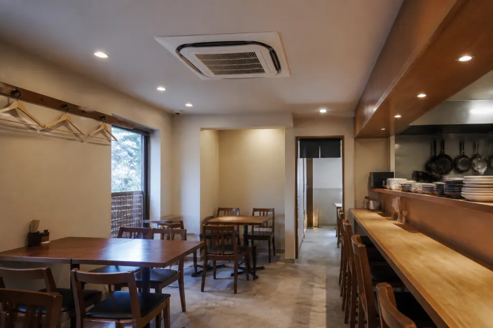木のテーブルとカウンター席が並ぶ落ち着いた飲食店の店内